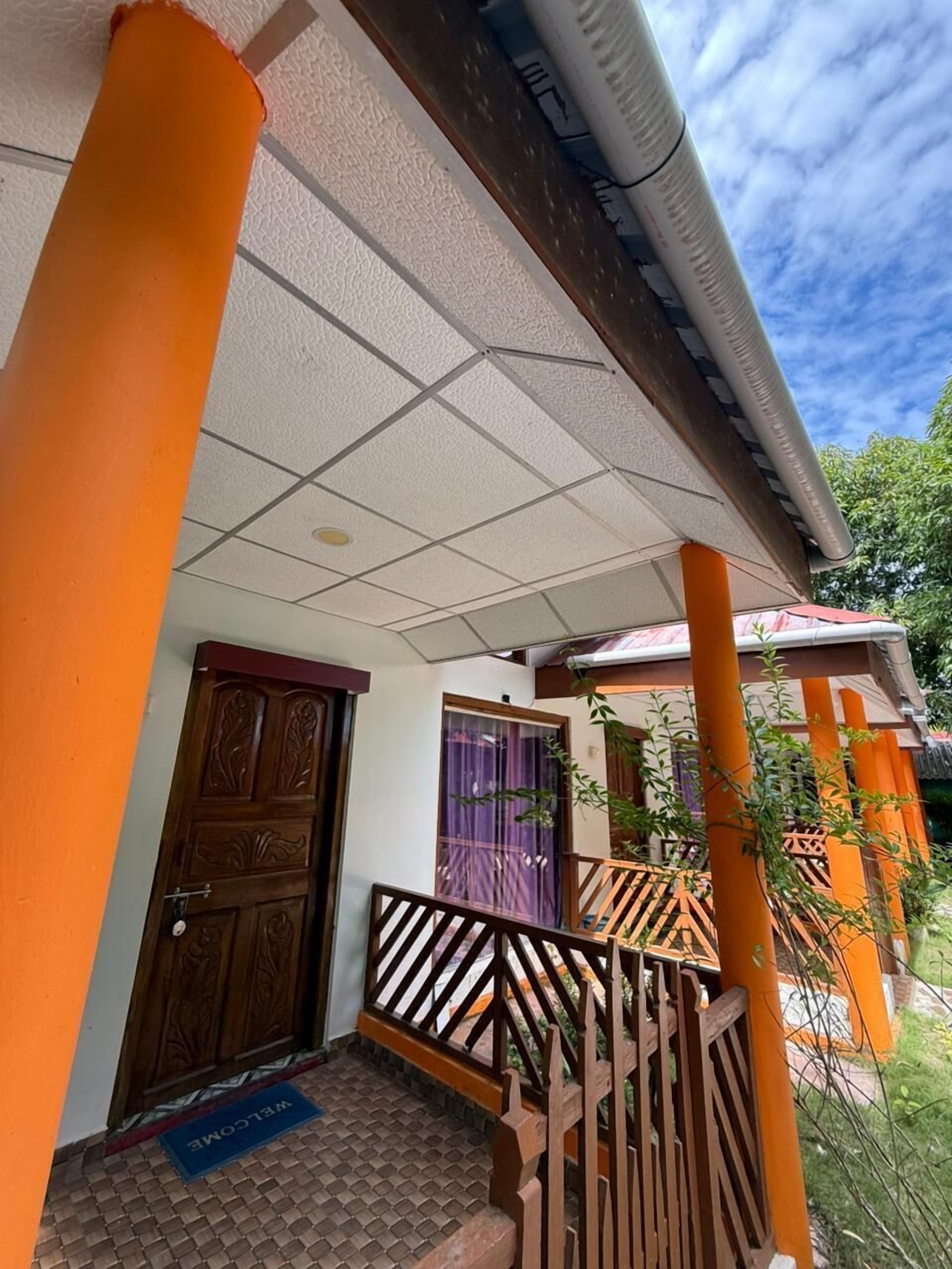 A building with a tiled entrance, a wooden door, and a balcony with a railing.