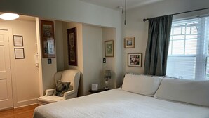 A bedroom with a bed, a chair, a nightstand, and a window with curtains. - Romantic Bed and Breakfast Getaway with an Indoor Pool near Lake Geneva, Wisconsin (Elkhorn)
