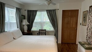 A bedroom with a bed, a nightstand, a chair, a door, and a window with curtains. - Romantic Bed and Breakfast Getaway with an Indoor Pool near Lake Geneva, Wisconsin (Elkhorn)