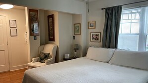 Une chambre à coucher avec un lit, une chaise, une table de chevet et une fenêtre avec des rideaux.