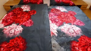 Een bed met een bloemenprint sprei en twee kussens.
