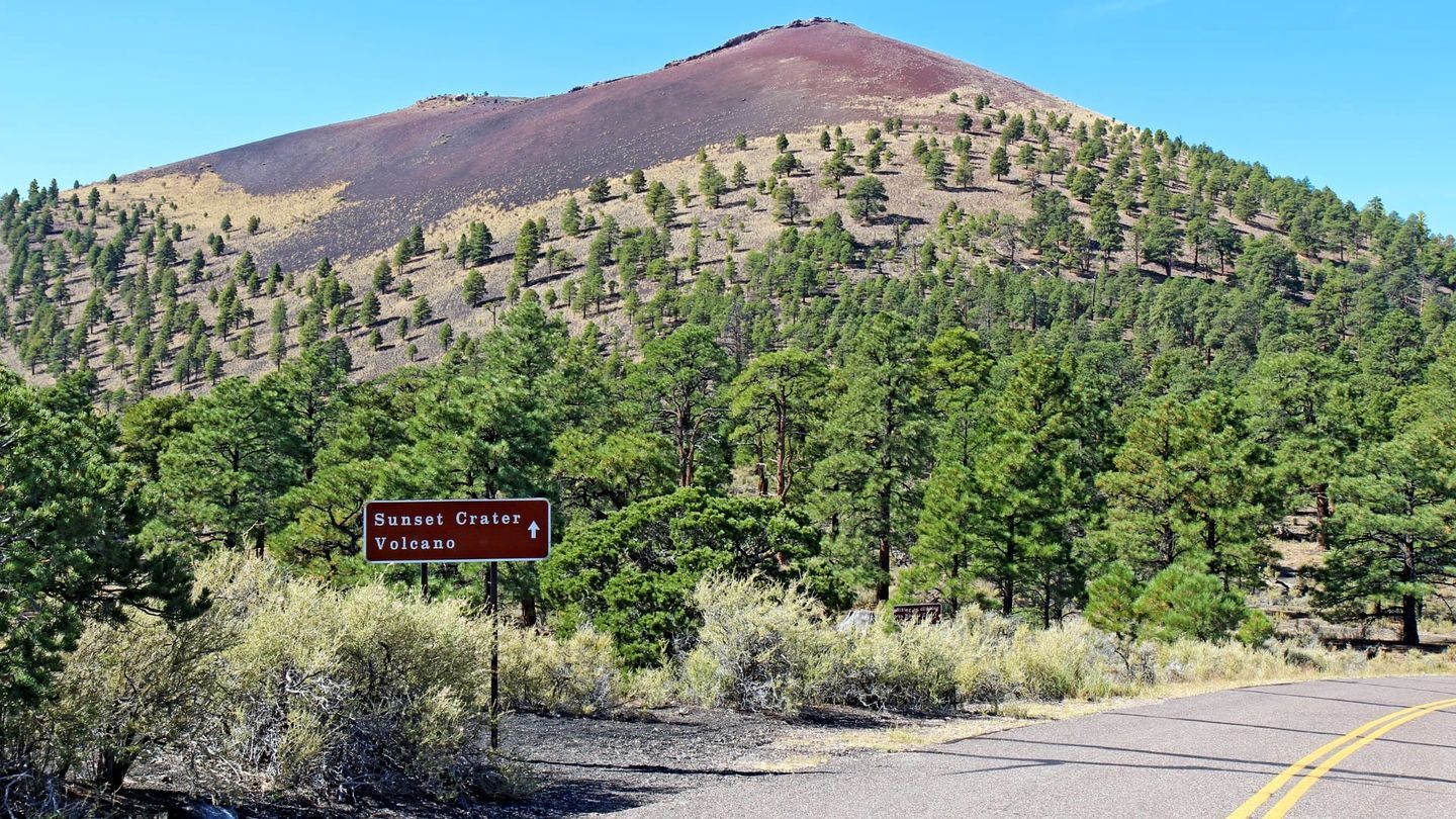 A road sign indicating directions to Sunset Crater and Volcanic areas.