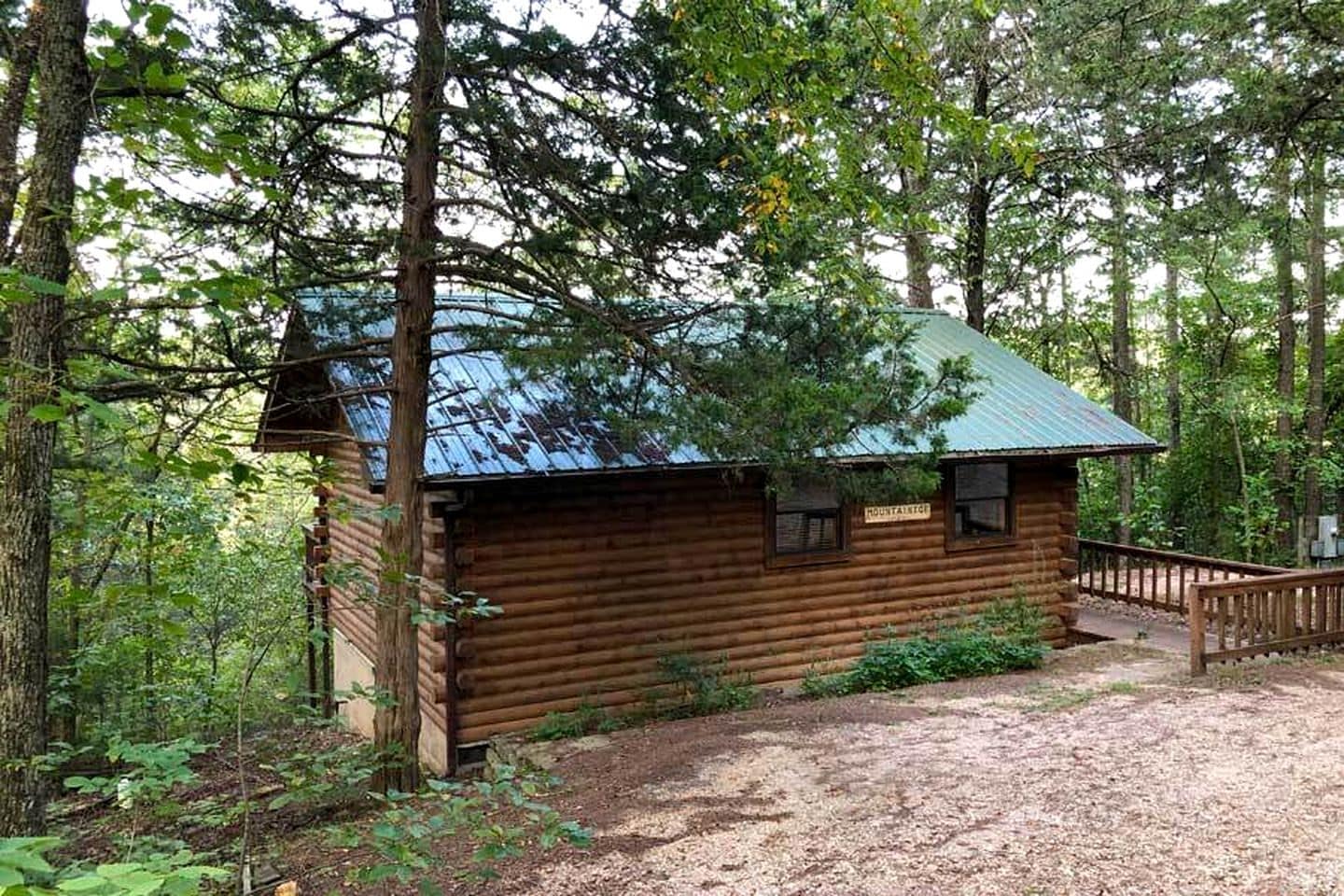 Eine rustikale Holzhütte mit einem Metalldach, umgeben von dichtem Wald.