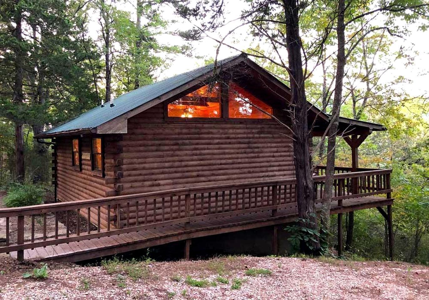 Een houten hut met een balkon, omringd door bomen.