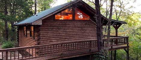 Une cabane en bois dotée d’un balcon, entourée d’arbres.