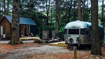 A forested campsite with a cabin and a vintage camper.