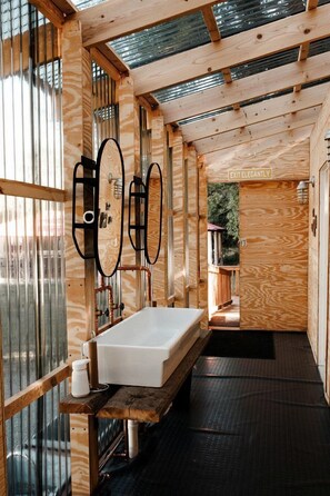 A wooden interior with a sink, mirror, and a sign reading 'EXIT ELEGANTLY.'