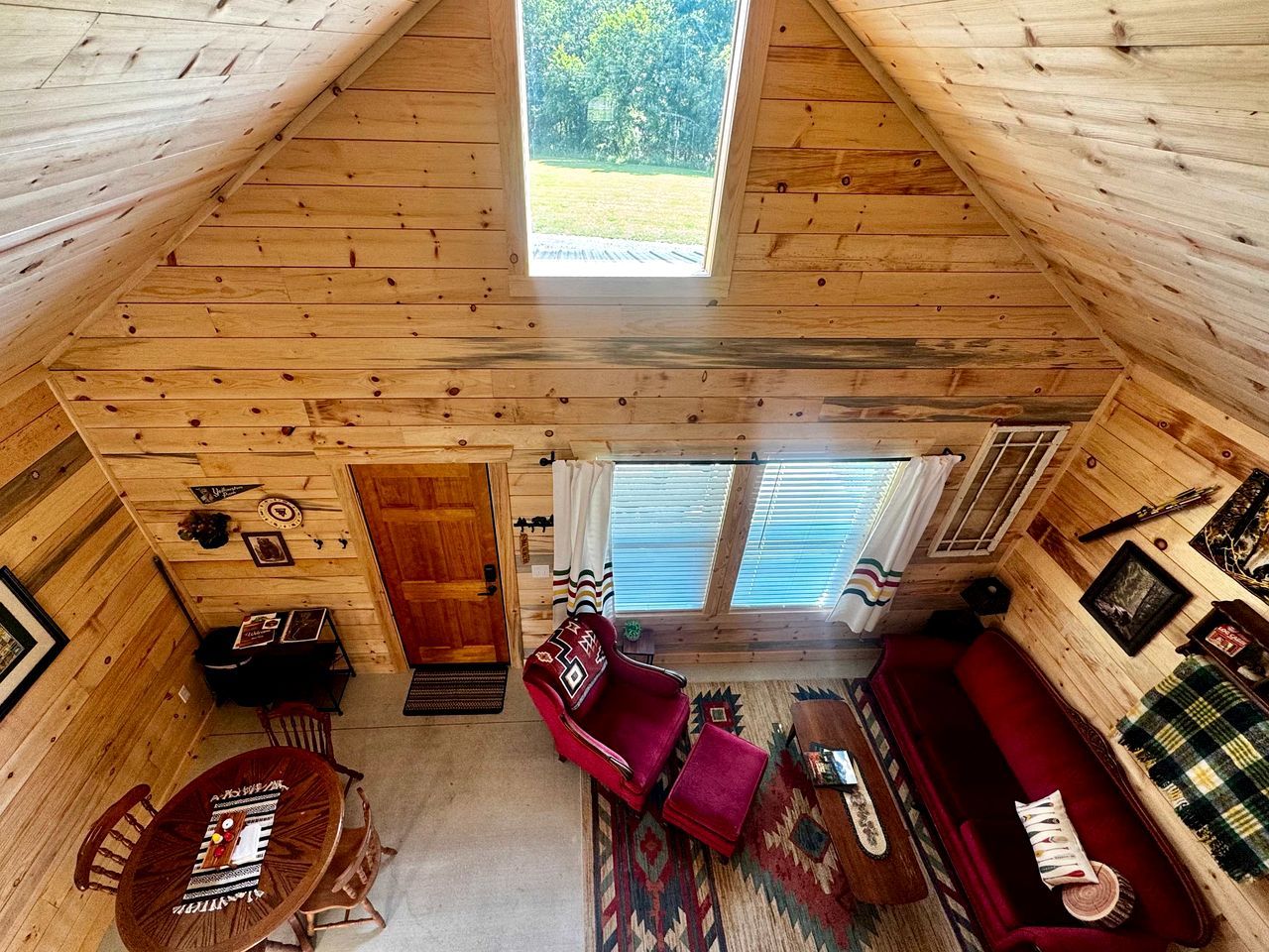 L’intérieur d’un chalet accueillant, avec un coin repas, un canapé rouge et une grande fenêtre.