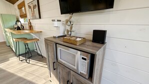 Ett kök med mikrovågsugn, kaffebryggare och en tv som är monterad på väggen.