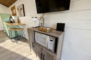 Una cocina equipada con microondas, cafetera y televisor montado en la pared.