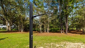 En metallkonstruktion med en skylt som lyder ”Vista Verde Farm Retreat”, placerad i ett skogsområde med gräs och träd.