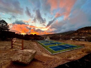 Una cancha de tenis con una valla de madera y una roca al frente.