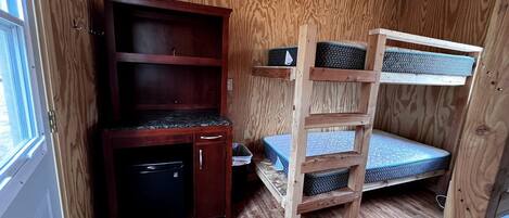 Una habitación pequeña con una cama nido, un mueble de madera y una ventana.
