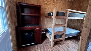 Una habitación pequeña con una cama nido, un mueble de madera y una ventana.