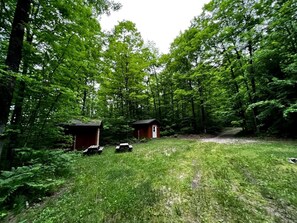 Metsäinen alue, jossa on kaksi pientä puumökkiä ja piknikpöytiä.