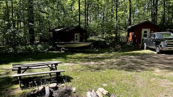 A cabin with a dock, a picnic table, and a truck parked nearby.