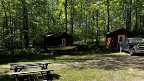 A cabin with a dock, a picnic table, and a truck parked nearby.