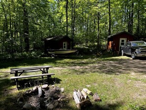 A cabin with a dock, a picnic table, and a truck parked nearby. - Charming Cabin in the Trees near Boulder Lake for an Amazing Escape near White Lake, Wisonsin (White Lake)