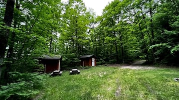 A forested area with two small wooden cabins and picnic tables.