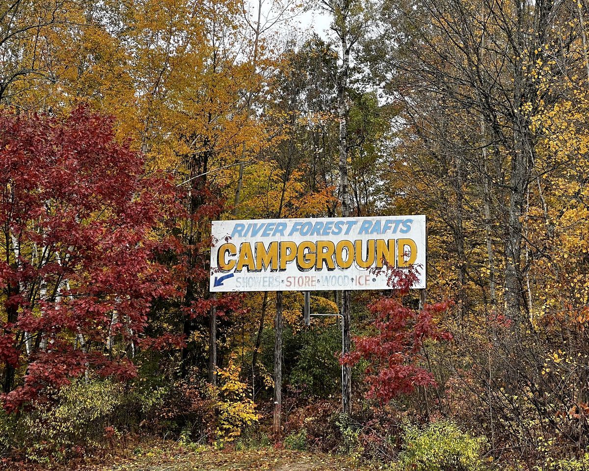 A sign for River Forest Rafts Campground with amenities listed.
