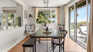 Comedor con mesa de madera, sillas y vista a un patio exterior a través de un ventanal.