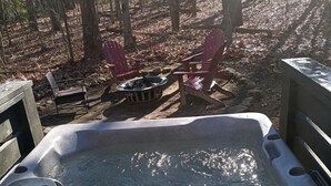 A hot tub in a forested area with chairs and a fire pit. - Luxurious Tiny Cabin with Hot-Tub and Fire Pit in Tennessee (Monteagle)