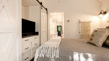 A bedroom with a bed, a television, a wardrobe, and a door leading to a bathroom.