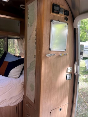 Un interior de madera con una cama, un mapa y una pequeña decoración de pez.