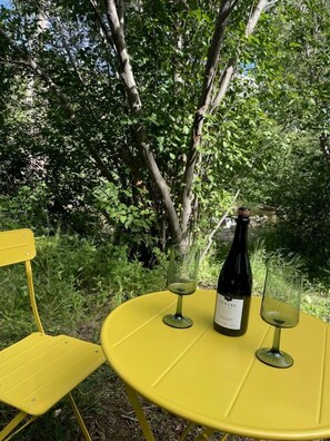 Una mesa amarilla al aire libre con una botella de vino y dos copas.