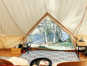A tent with a view of a forest and water, a patterned rug, and wooden furniture. - Stunning Safari Tent Rental on the Pecos River, for Great Glamping Getaways in New Mexico (Pecos)