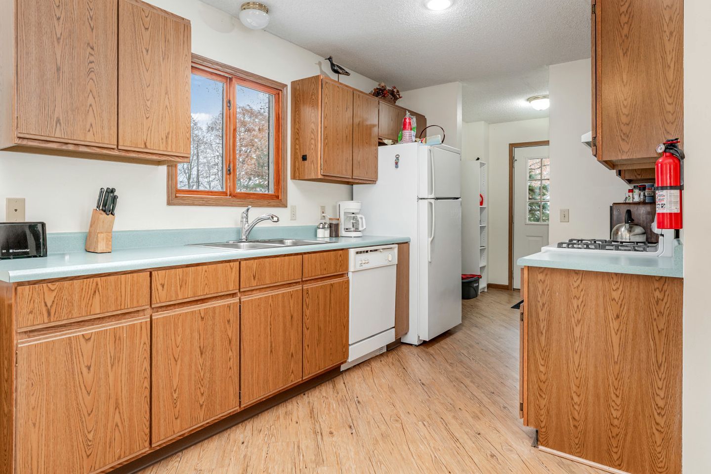 A kitchen with wooden cabinets, a white refrigerator, a sink, and a window.