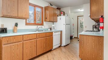 A kitchen with wooden cabinets, a white refrigerator, a sink, and a window.