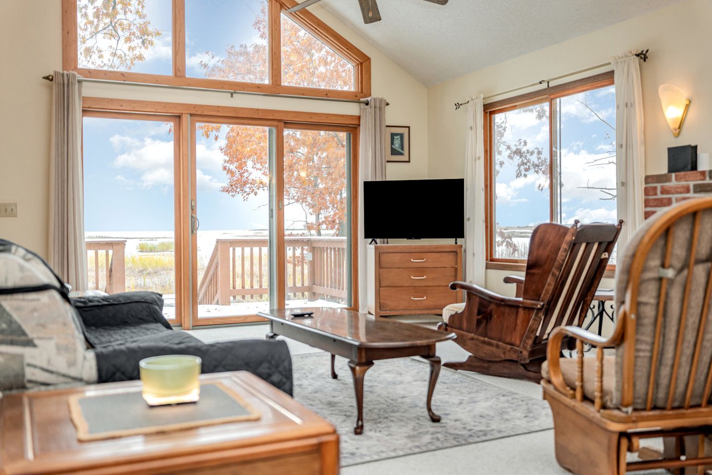 A room with a large sliding glass door, a flat-screen TV, wooden furniture, and a view of the outdoors.
