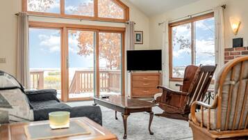 A room with a large sliding glass door, a flat-screen TV, wooden furniture, and a view of the outdoors.