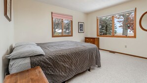 A bedroom with a bed, two windows, a dresser, and a ceiling light. - Comfy Sweet Cottage with BBQ Surrounded by Nature in Michigan (Au Gres)