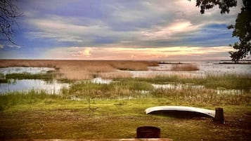A bench overlooking a marshy landscape with a sunset.