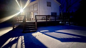 A snow-covered outdoor area with a wooden bench and a house in the background. - Comfy Sweet Cottage with BBQ Surrounded by Nature in Michigan (Au Gres)