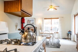 A kitchen with a stove, kettle, and wooden cabinets. - Comfy Sweet Cottage with BBQ Surrounded by Nature in Michigan (Au Gres)