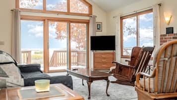 A room with a large sliding glass door, a flat-screen TV, wooden furniture, and a view of the outdoors.
