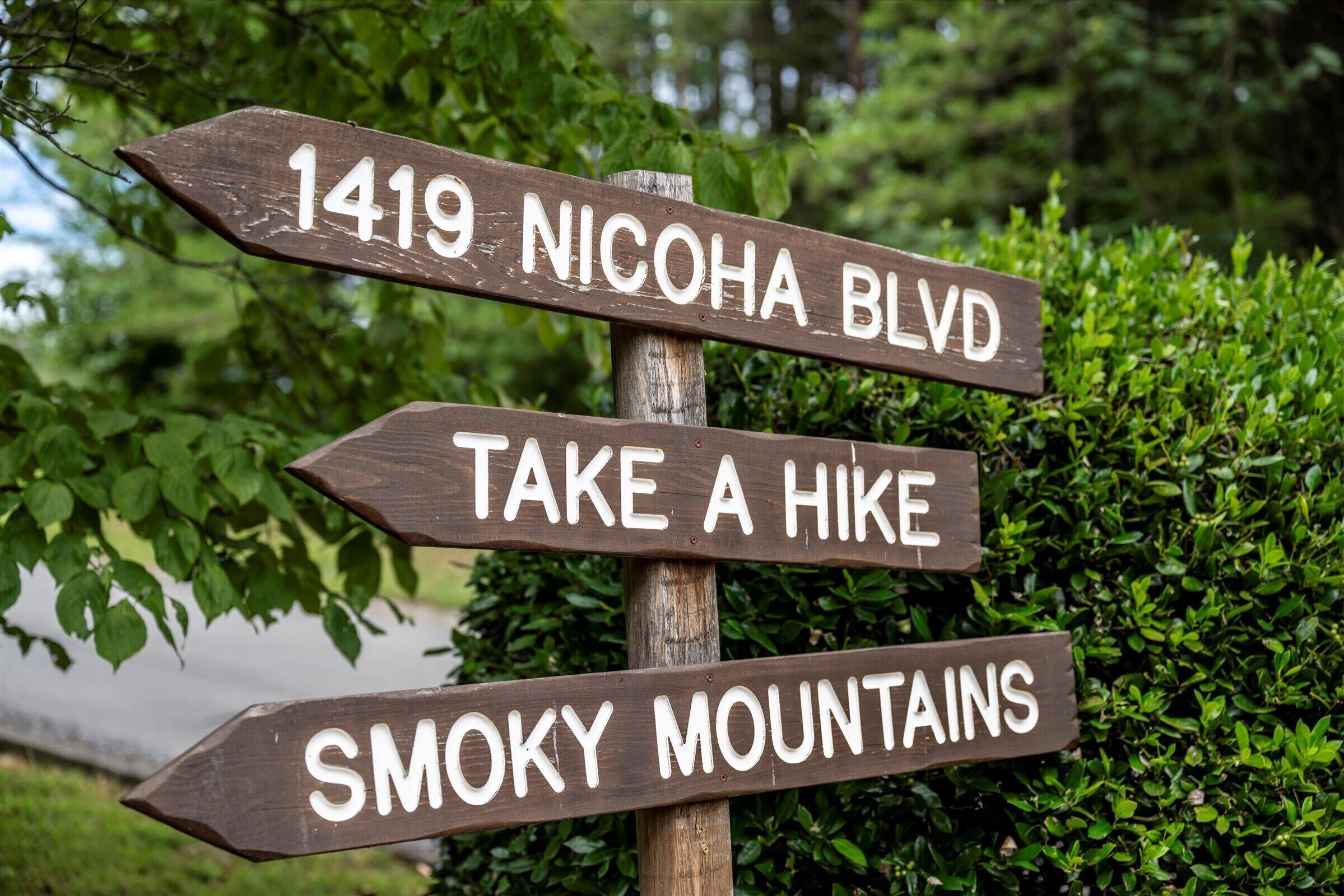 Un cartel de madera con indicaciones hacia el bulevar Nicoha, una caminata y las Montañas Humeantes.
