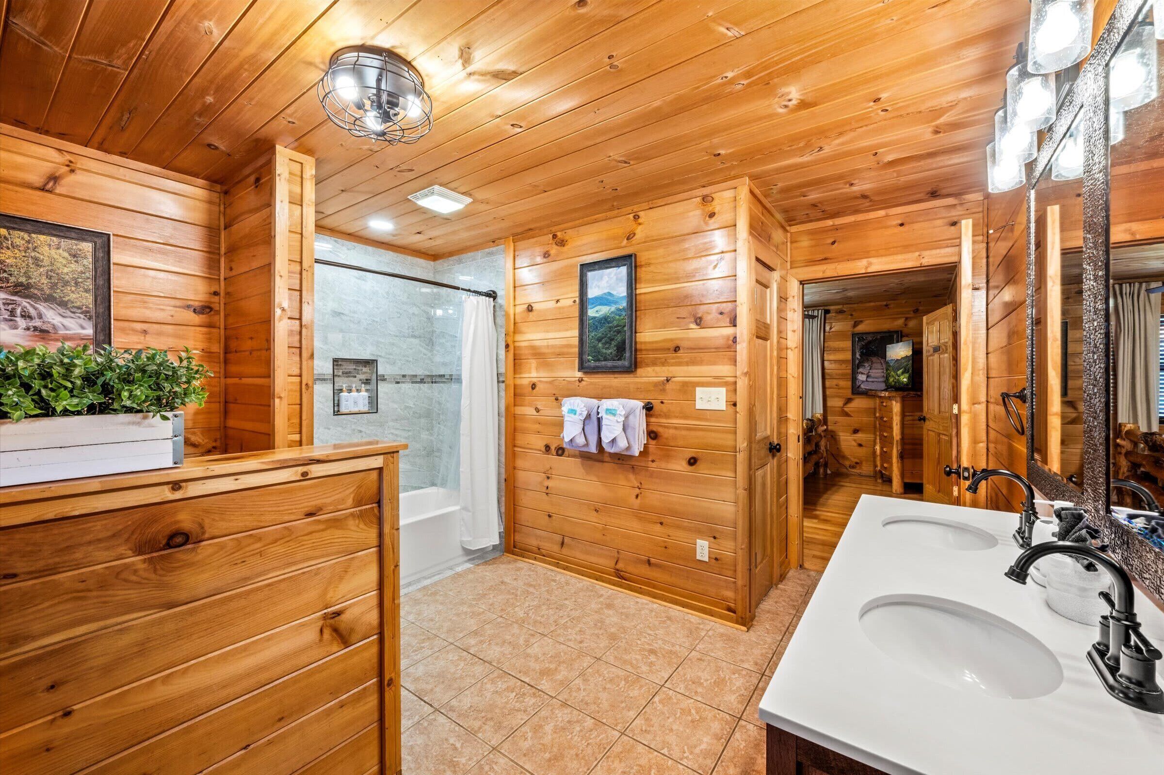 A wooden cabin bathroom with two sinks, a shower, and a large mirror.
