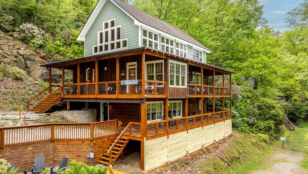 A two-story wooden cabin with a deck, a staircase, and a gravel path. - Incredible Riverfront Cabin Surrounded by Trees for an Unforgettable Escape in Nature in Blue Ridge, Georgia (Blue Ridge)