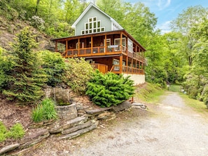 A wooden cabin with a porch, surrounded by dense greenery and a gravel path leading to it. - Incredible Riverfront Cabin Surrounded by Trees for an Unforgettable Escape in Nature in Blue Ridge, Georgia (Blue Ridge)