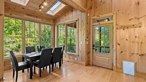 A wooden interior with a dining table, chairs, and large windows. - Incredible Riverfront Cabin Surrounded by Trees for an Unforgettable Escape in Nature in Blue Ridge, Georgia (Blue Ridge)
