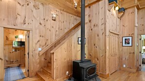 A wooden interior with a staircase, a fireplace, and a small kitchen area with a microwave. - Incredible Riverfront Cabin Surrounded by Trees for an Unforgettable Escape in Nature in Blue Ridge, Georgia (Blue Ridge)
