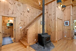 A wooden interior with a staircase, a fireplace, and a small kitchen area with a microwave. - Incredible Riverfront Cabin Surrounded by Trees for an Unforgettable Escape in Nature in Blue Ridge, Georgia (Blue Ridge)