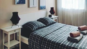 Ein Schlafzimmer mit einem Bett, zwei Nachttischen, einer Pendelleuchte und drei gerahmten Bildern an der Wand.
