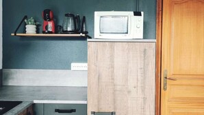 Eine Küche mit Mikrowelle, Kaffeemaschine und Wasserkocher auf einem Regal, einem Holzschrank und einer Holztür.