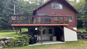 Eine zweistöckige Holzblockhütte mit Balkon, Garage und einer Steinmauer im Hintergrund.