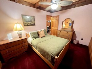 A bedroom with a bed, wooden dresser, nightstand, lamp, and a ceiling fan. - Fantastic Lakefront Wooden Cabin Settled Between Trees in Stratton, Vermont (Stratton)